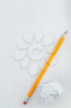 pencil and crumpled paper ball on checked background