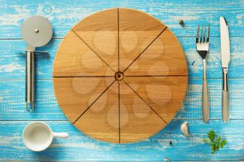 pizza cutting board and utensils at wooden table