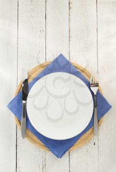 knife and fork with plate at napkin on wooden background