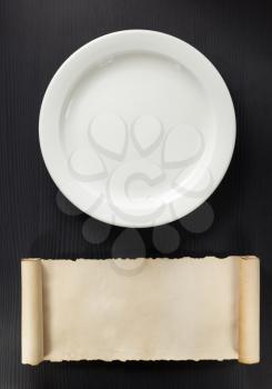 plate and scroll on wooden background