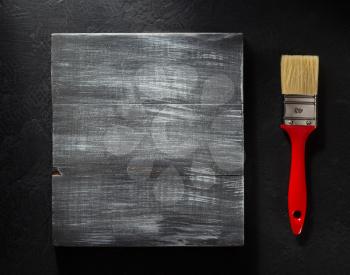 paintbrush and wooden board on black background