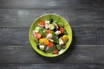 fresh greek salad in plate on wooden table
