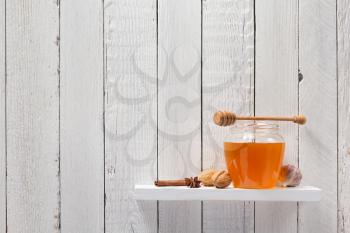 glass jar of honey on wooden shelf background