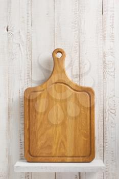 cutting board on shelf at white wooden background
