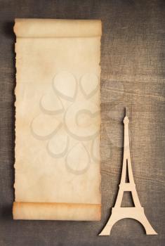 old retro aged paper parchment  and eiffel tower toy at wooden background