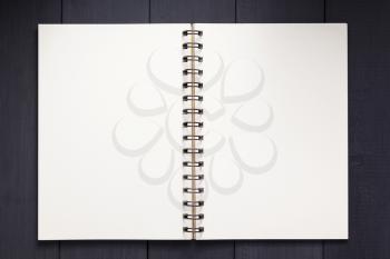 notepad or notebook paper at black wooden background surface table, top view