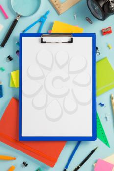 paper clipboard and school accessories at abstract background surface