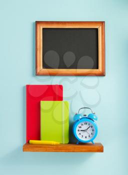 notepad and alarm clock on shelf at wall background surface