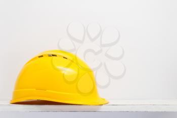 construction helmet on wooden shelf at white background texture wall
