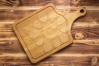 cutting board at rustic wooden plank background, top view