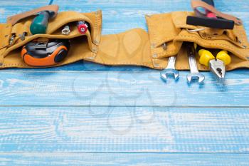 tools and instruments in belt on wooden table in front, plank board background texture surface