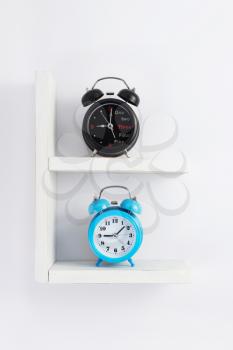 alarm clock at wooden shelf on white background