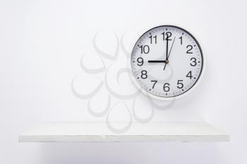 wall clock and wooden shelf on white background