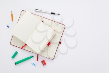 notebook and stationary at white paper background, top view