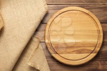 pizza cutting board and sack hessian cloth at rustic wooden plank board background, top view