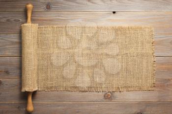 rolling pin and sacking burlap at wooden board rustic  plank table background, top view