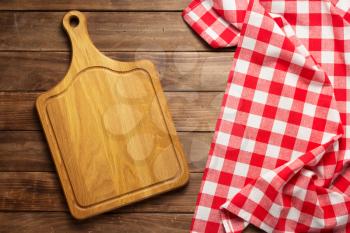 pizza cutting board and kitchen napkin cloth at rustic wooden plank board background, top view