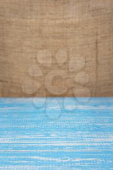 wooden board plank table and burlap hessian sacking background, table in front view