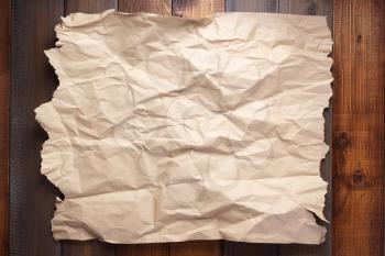wrinkled paper at wooden plank wall or table board  background