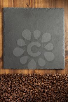 coffee concept beans and slate stone on wooden background, top view