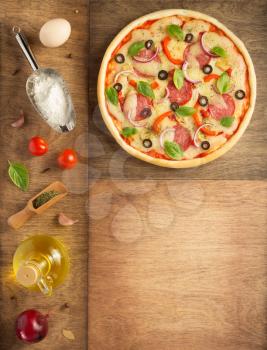 pizza and food ingredients at wooden table, top view