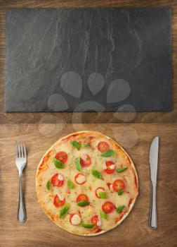 margarita pizza at wooden table and slate stone board, top view