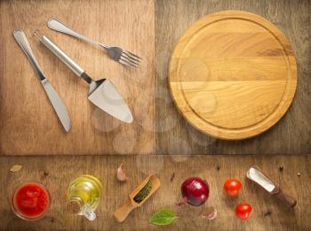 food ingredients and spices with cutting pizza board at wooden table, top view