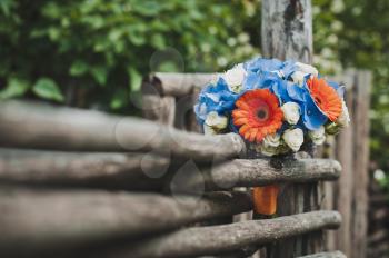 The bouquet from flowers lies on a wattled fence.