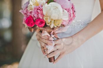 Hands of the woman hold a bunch of flowers.
