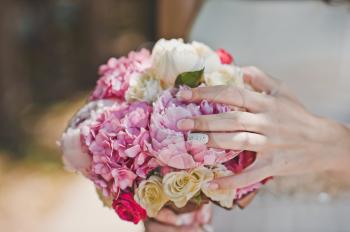 Hands of the woman hold a bunch of flowers.