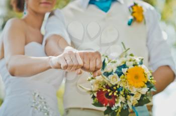 Newly-married couple shows rings on fingers compressed in fists.