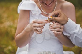 Hands of the newly-married couple hold wedding rings.