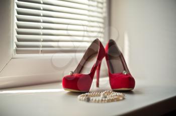 Red shoe on a window sill and a necklace.