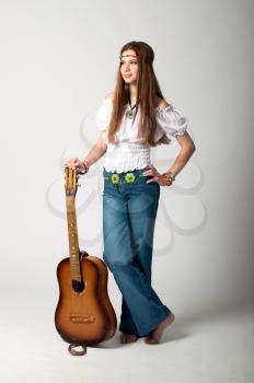 Studio photo of the girl with long hair with a guitar on a grey background.