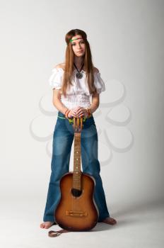 Studio photo of the girl with long hair with a guitar on a grey background.