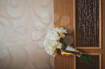 The bridal bouquet lies on the door handle in a room.