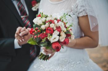 Bouquet in hands of the newly-married couple.