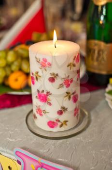 Decorative big candle with patterns in the form of red and pink flowers.