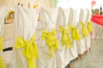Registration of chairs with yellow bows in a festive hall.