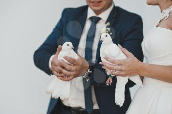 Newly-married couple holds pigeons.