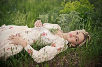 The girl lies on a green grass.
