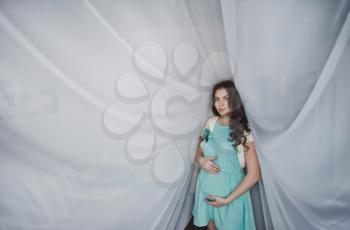 The girl during pregnancy in beautiful curtains.