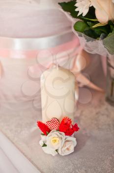 Candle with a beautiful bow and roses on a table