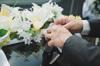 The groom decorates the car with flowers.