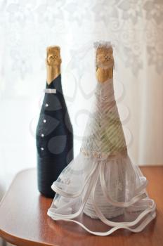 Dresses of the groom and the bride on bottles with champagne.