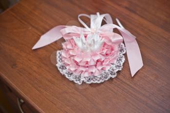 Openwork ornament on a foot of the bride from a pink and white fabric.