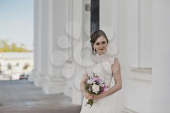 Portrait of a girl in a white dress and veil around the columns.