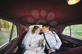 The couple sitting in vintage car.