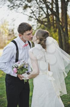 Newlyweds kissing on the background of the forest.