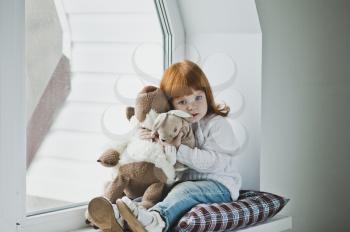 Little girl with red hair plays with a toy.